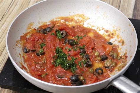 Sartén con ingredientes de la salsa puttanesca cocinándose a fuego medio