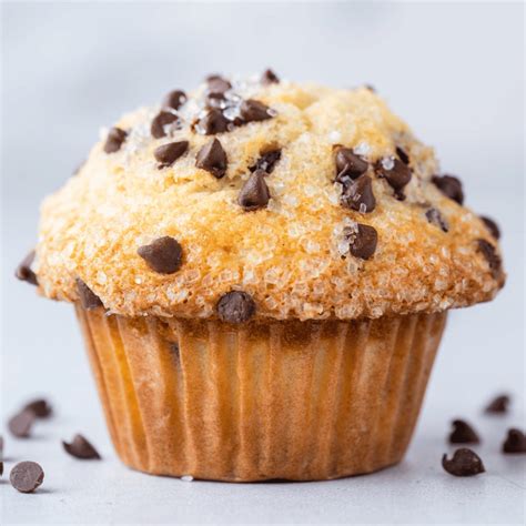 Imagen de primer plano de muffins caseros con chips de chocolate, resaltando su textura esponjosa y copete alto.