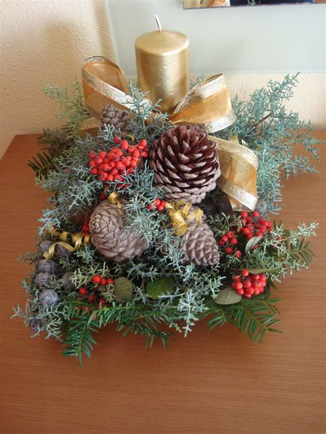 Centro de mesa navideño con piñas decoradas, velas y cintas