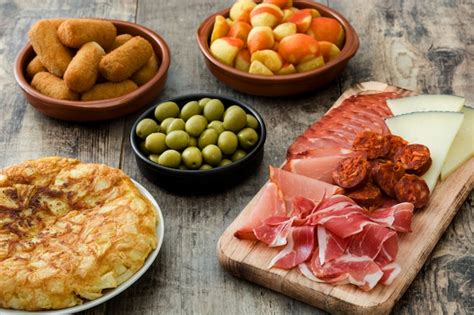 Variedad de tapas españolas fritas, incluyendo calamares, croquetas y patatas bravas.
