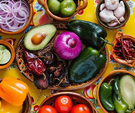 Fotografía de Martha Ortiz en su cocina, destacando el uso de ingredientes tradicionales mexicanos con un enfoque artístico y contemporáneo.