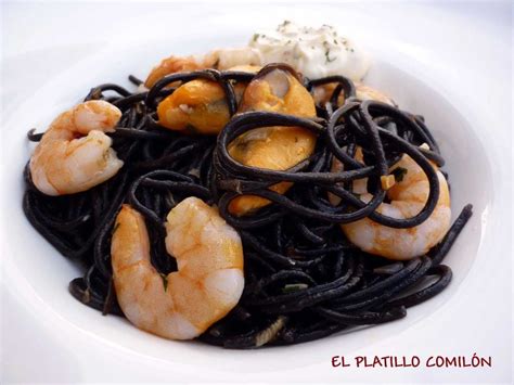 Plato de espaguetis con tinta de calamar servido, decorado con ralladura de limón y hojas de menta