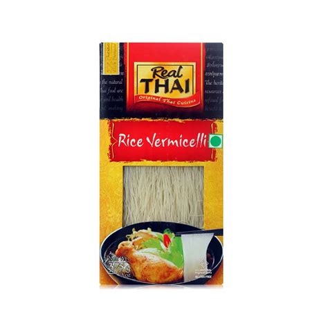 Imagen de un paquete de fideos de arroz Real Thai junto a ingredientes frescos tailandeses como limas, chiles y albahaca