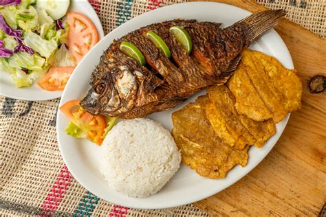 Pescado frito servido con patacones y ensalada