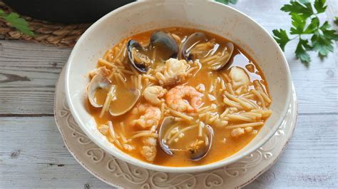 Imagen de una sopa de marisco bien presentada en una olla de hierro con marisco fresco y detalles decorativos