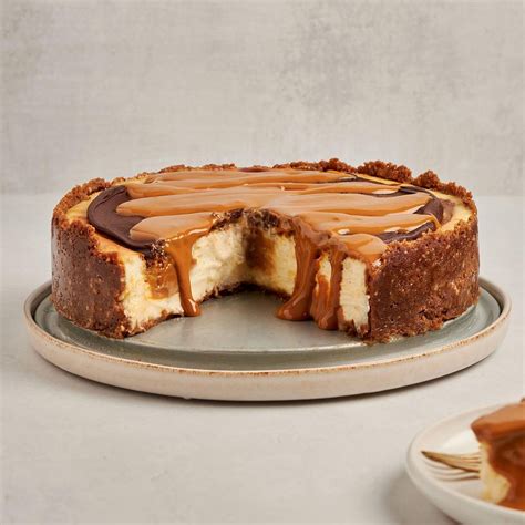 Ilustración de un cheesecake de dulce de leche terminado, decorado con hilos de dulce de leche y migas de galleta.