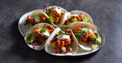 tres tacos veganos de coliflor rebozada, con aguacate y salsa ranch, sobre un fondo rústico