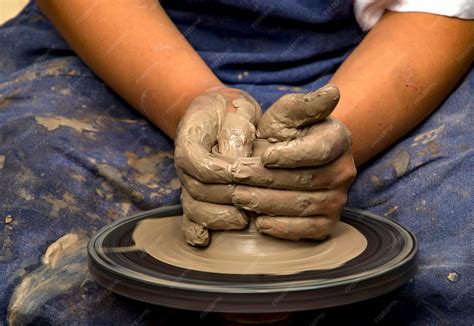 Niño o niña concentrado modelando arcilla en un taller de cerámica.