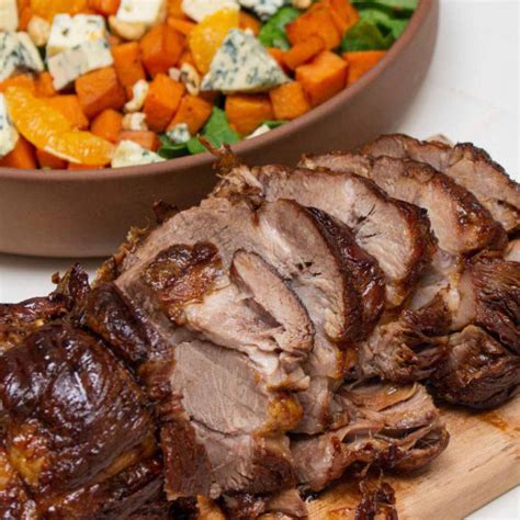 Imagen de un plato servido con bondiola braseada, batatas y una reducción oscura.