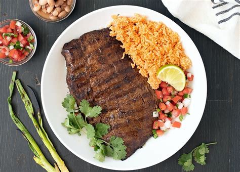 Plato de carne asada con un generoso acompañamiento de salsa chimichurri.