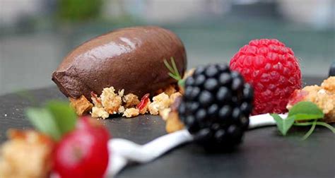 Plato de postre con quenelle de mousse de chocolate y frutos rojos