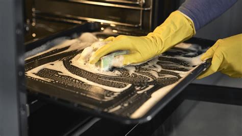Persona limpiando una bandeja de horno con una esponja suave
