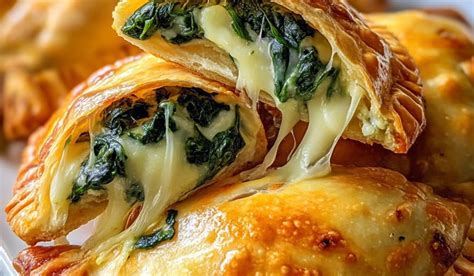 Empanadas de espinaca con queso recién horneadas y doradas, presentadas en una tabla de madera