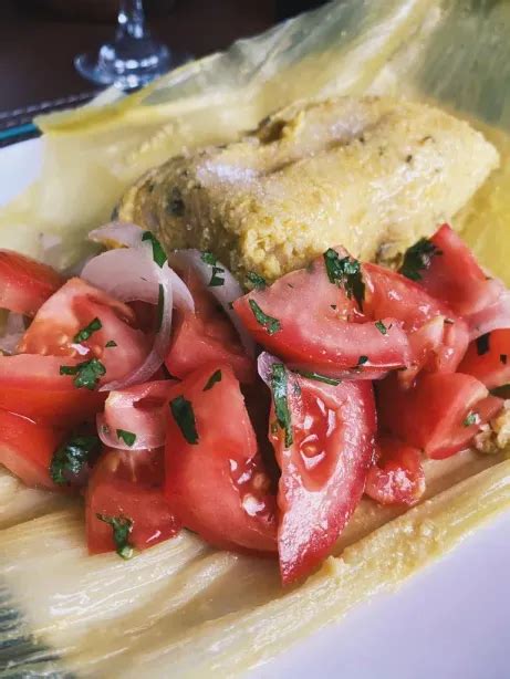 Humitas chilenas servidas con azúcar espolvoreada y una ensalada de tomate y cebolla