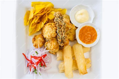 Plato de chicharrón de pescado servido con yuca frita, salsa criolla y rodajas de limón.
