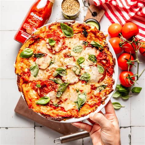 pizza de coliflor con vegetales frescos sobre una tabla de madera