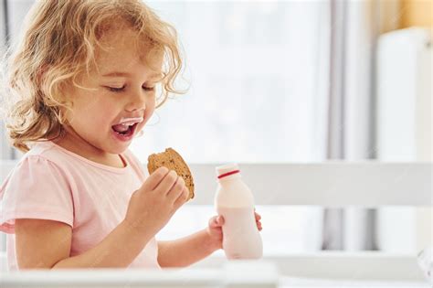 Persona comiendo galletas y bebiendo leche, con frutas en la mesa