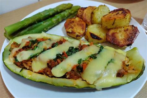 Plato terminado de zapallo italiano relleno servido con una ensalada fresca al lado