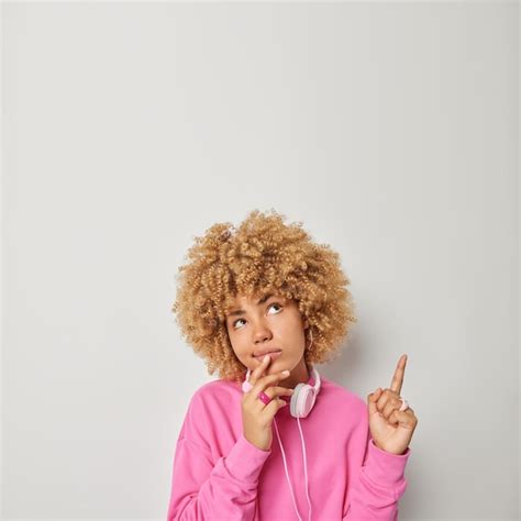 Fotografía de una mujer afrodescendiente con cabello rizado, pensativa