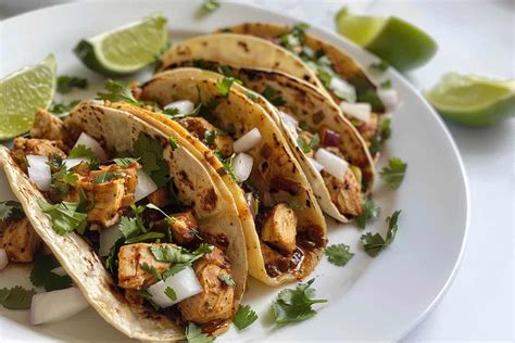Plato de tacos de pollo con diferentes salsas y vegetales