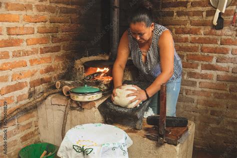 Mujer indígena preparando tortillas en un metate