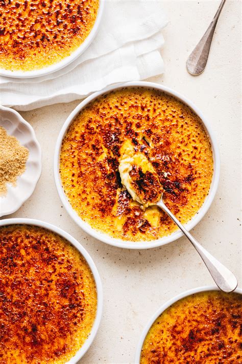 Fotografía cenital de varias raciones de creme brûlée servidas en recipientes de cerámica individuales con una costra de azúcar perfectamente caramelizada