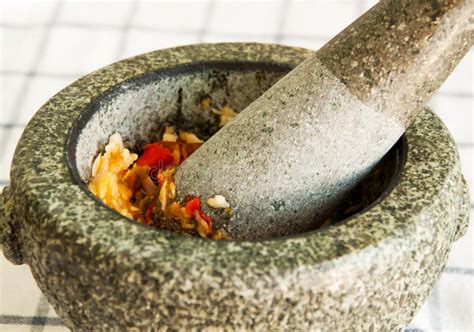 Imagen de los ingredientes machacados en un mortero: rodajas de naranja, hierbabuena y azúcar moreno.