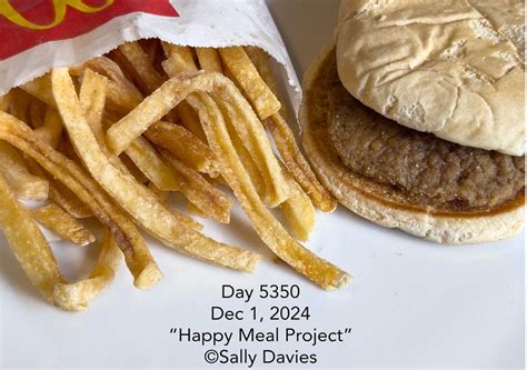 fotografía de Sally Davies con la hamburguesa y patatas del Happy Meal en el mostrador de su cocina, con sus perros observándola