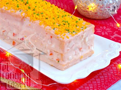 Imagen representativa de un pastel de marisco servido en lonchas con guarnición de salsa rosa y brotes frescos.