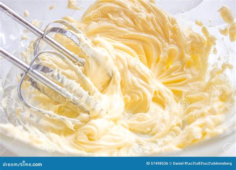 Esquema visual que muestra el batido de la mantequilla, la incorporación de la ralladura de naranja fresca y el puré de frambuesas para lograr una textura homogénea.
