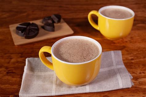 Taza de Atole con Chocolate Abuelita humeante con pan de dulce de fondo