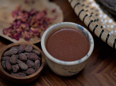 Imagen de un tazón con cacao ceremonial granulado y una taza de chocolate caliente