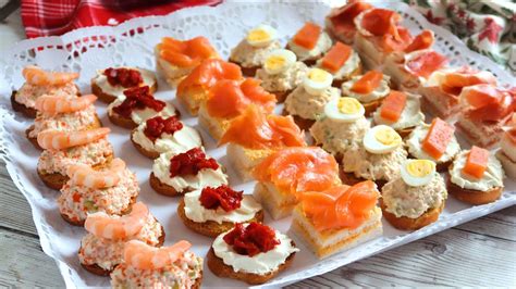 Bandeja variada de canapés coloridos y presentados de forma profesional sobre una tabla de madera