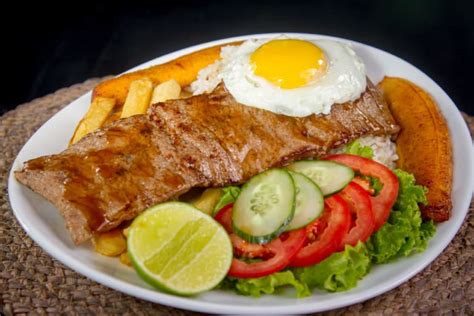 Fotografía de un plato de bistec a lo pobre servido en un restaurante, con todos sus acompañamientos.