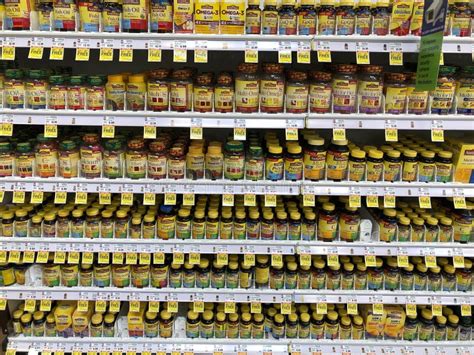 Estantería de farmacia con diversos suplementos alimenticios y vitaminas organizados por categorías de salud