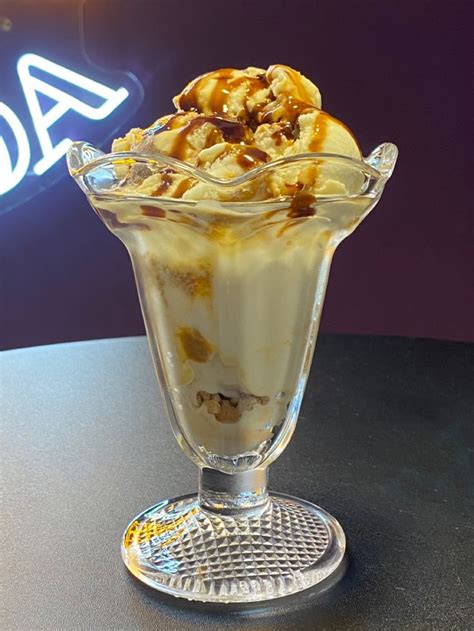 Fotografía profesional de helado artesanal servido en una copa de vidrio transparente, resaltando su textura cremosa.