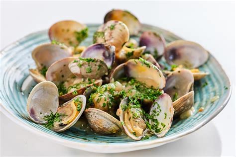 Ilustración de un plato de almejas a la marinera con perejil fresco picado.