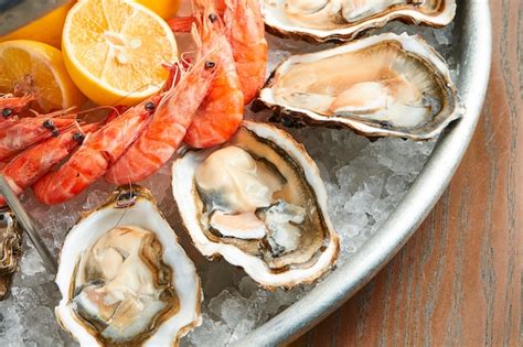 Foto de mariscos frescos y variados sobre hielo, con toques de limón y perejil, destacando su calidad.