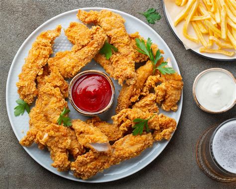 Imagen de fingers de pollo dorados y crujientes horneados, servidos con una salsa saludable.