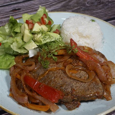 Plato de bistec encebollado servido con arroz y ensalada