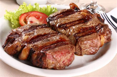 Fotografía de un bife de chorizo en su punto servido en un plato de madera, resaltando la calidad del corte