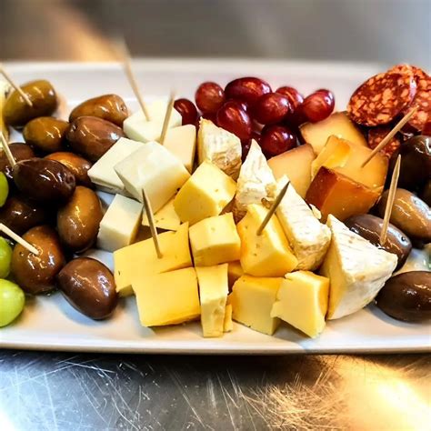 Tabla de quesos, aceitunas y ensalada verde acompañando una porción de tortilla