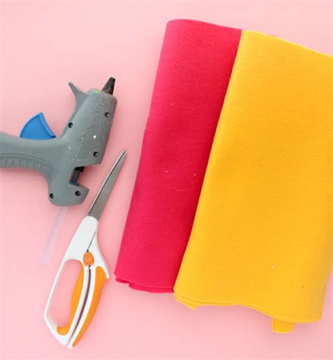Envase de plástico, fieltro amarillo, tijeras, pistola de pegamento y cinta de carrocero para hacer un macetero de piña.