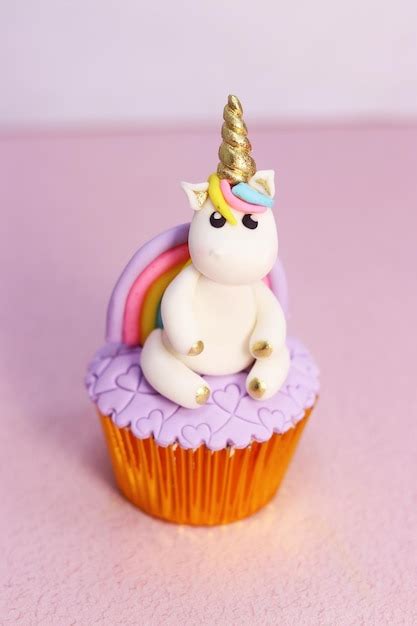 Primer plano de un cupcake de unicornio terminado, mostrando detalles de decoración con fondant y chispas.