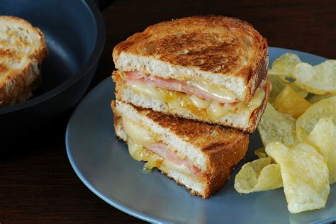 Imagen de un sándwich gourmet con mortadela, queso y cebolla caramelizada en pan rústico.