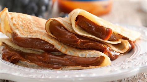 Ilustración de panqueques clásicos servidos con dulce de leche y frutas, destacando su versatilidad.