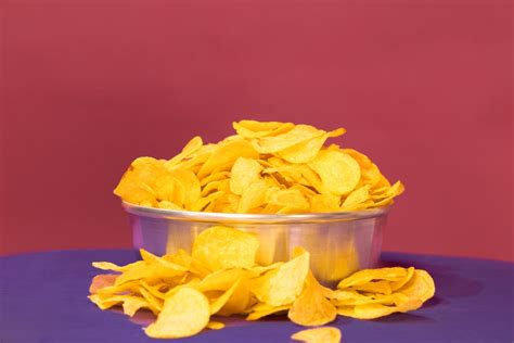 Fotografía cenital de un bol de patatas fritas recién hechas rodeado de diversos cuencos con salsas coloridas y texturas variadas.