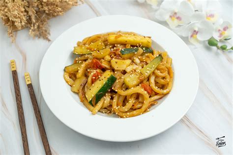 Fotografía cenital de un plato de Yaki Udon con pollo, verduras frescas y semillas de sésamo