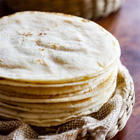 Tortillas de maíz siendo rellenadas con pollo desmechado.