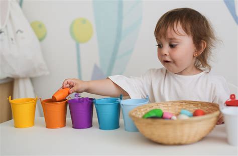 Niños clasificando palitos de helado de colores en diferentes recipientes